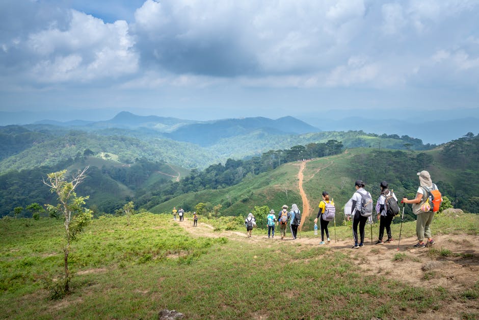 Group of hikers trekking through picturesque mountain landscape on a cloudy day.