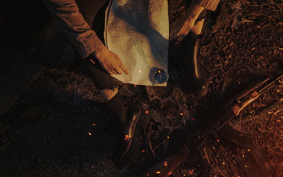 A person planning a journey using a map, compass, and military gear in a rugged outdoor setting.